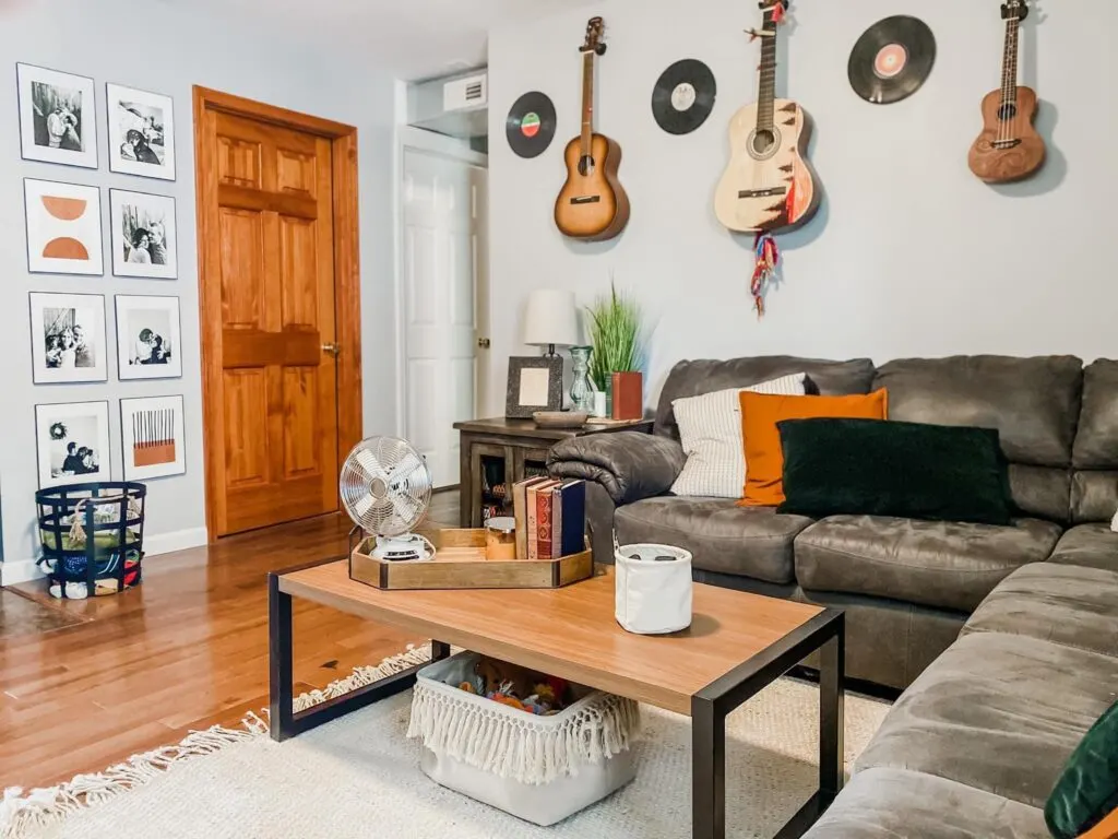 Living room with guitar decor and a wood-stained door with wood trim